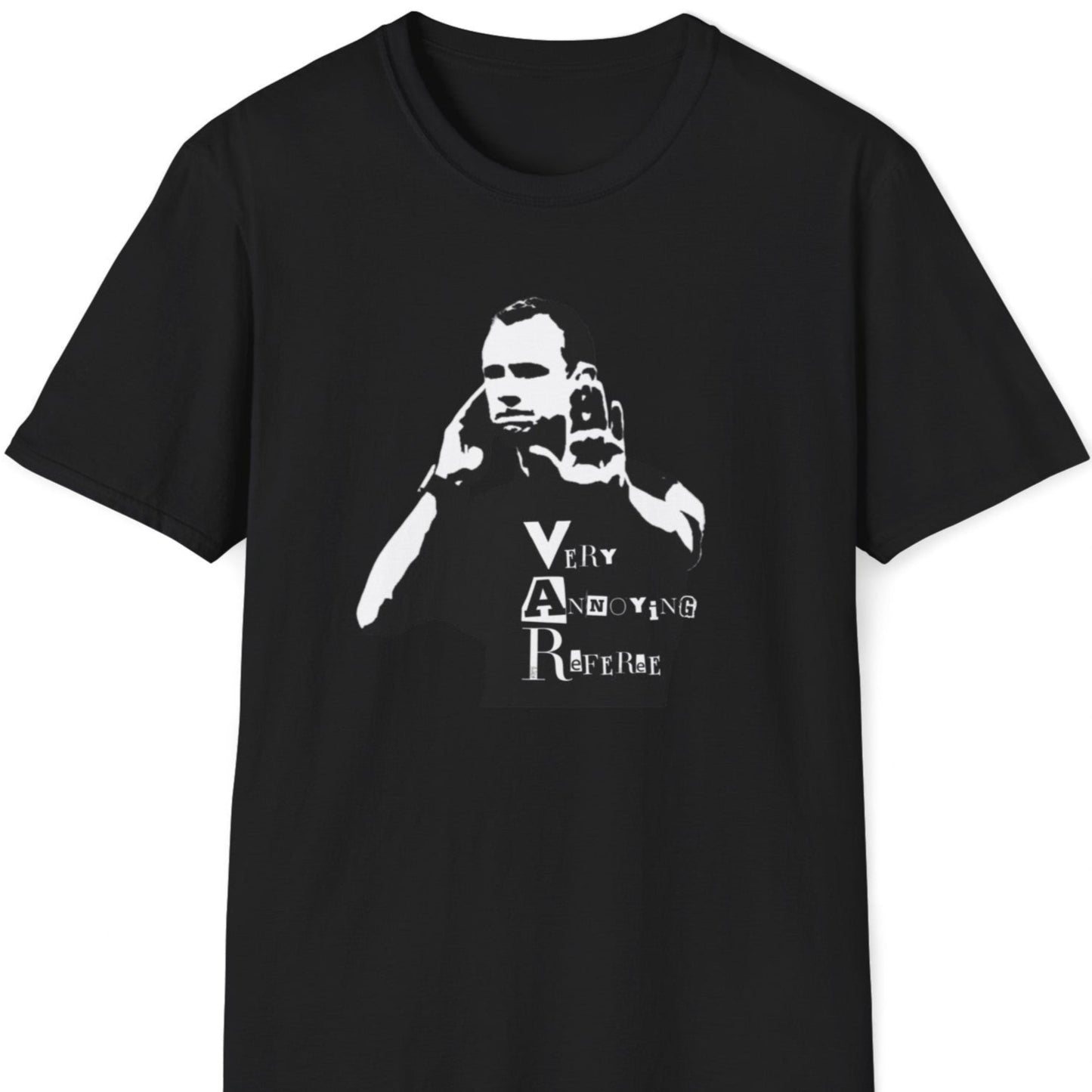 Skjeggete mann med blå caps og tatoveringer står mot en rusten metallvegg, iført en svart T-skjorte med et stilisert motiv av en dommer som bruker VAR, og teksten "Very Annoying Referee" i en klippet bokstavstil.