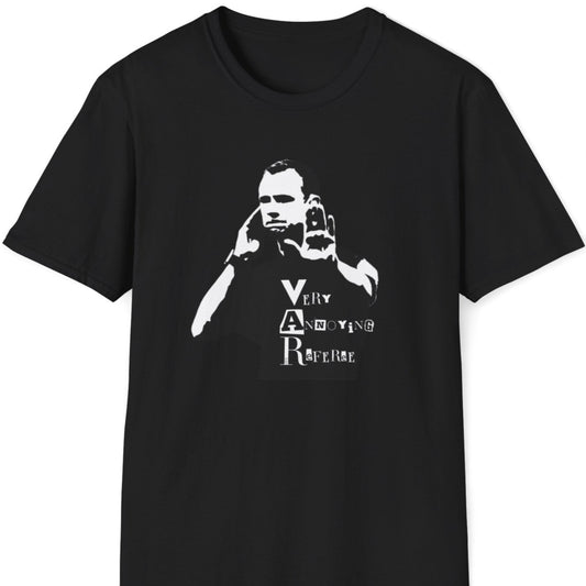 Skjeggete mann med blå caps og tatoveringer står mot en rusten metallvegg, iført en svart T-skjorte med et stilisert motiv av en dommer som bruker VAR, og teksten "Very Annoying Referee" i en klippet bokstavstil.
