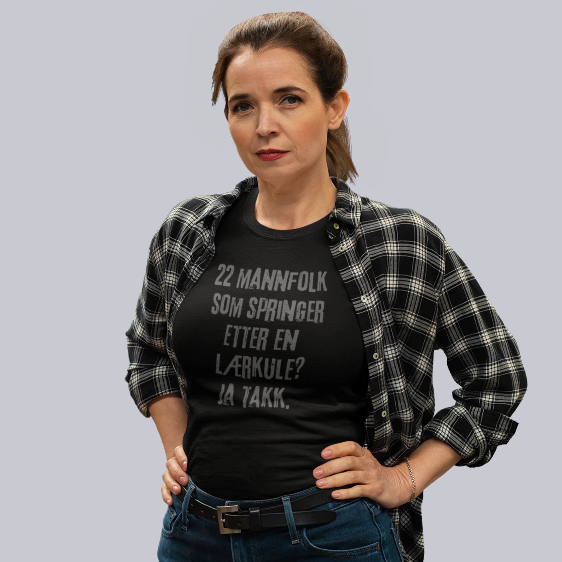 Kvinne iført svart T-skjorte med teksten "22 mannfolk som springer etter en lærkule? Ja takk."