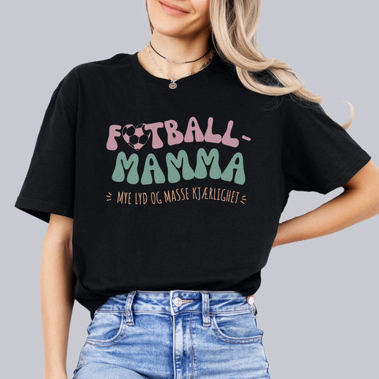 Kvinne i svart T-skjorte med teksten "Fotball-Mamma – Mye lyd og masse kjærlighet" i en fargerik, leken stil.






