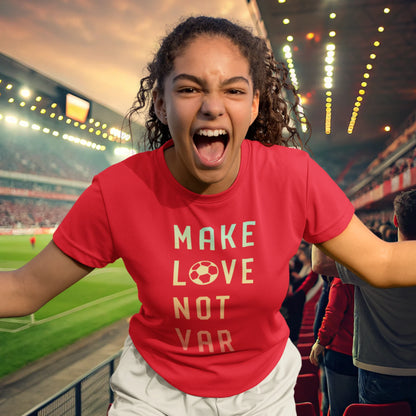 Engasjert fotballsupporter i rød T-skjorte med teksten "MAKE LOVE NOT VAR", hvor bokstaven "O" i "LOVE" er erstattet med en fotball. Hun roper og jubler på tribunen i et flombelyst stadion.