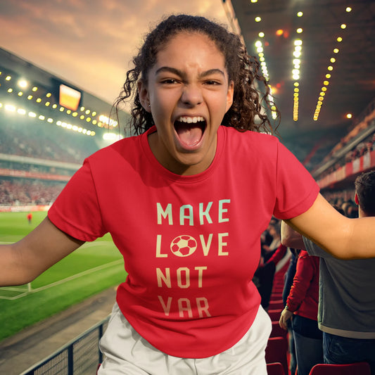 Engasjert fotballsupporter i rød T-skjorte med teksten "MAKE LOVE NOT VAR", hvor bokstaven "O" i "LOVE" er erstattet med en fotball. Hun roper og jubler på tribunen i et flombelyst stadion.